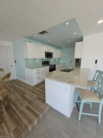 EAT-IN KITCHEN ALSO INCLUDES A BREAKFAST BAR.  DOOR SHOWN AT LEFT LEADS TO GARAGE.