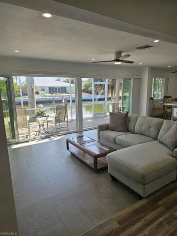 LIVING AREA SHOWING ENTRANCE TO LANAI.  VINYL PLANK FLOORING.  TILE FLOORING.  EASTERN EXPOSURE SCREENED LANAI.