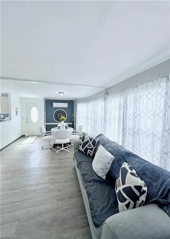Living room with wood finished floors and a wall mounted air conditioner