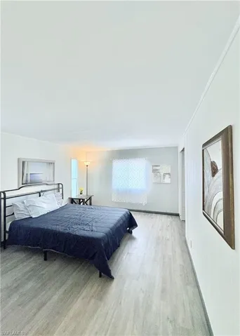Bedroom featuring light wood-style floors, wood walls, and ornamental molding