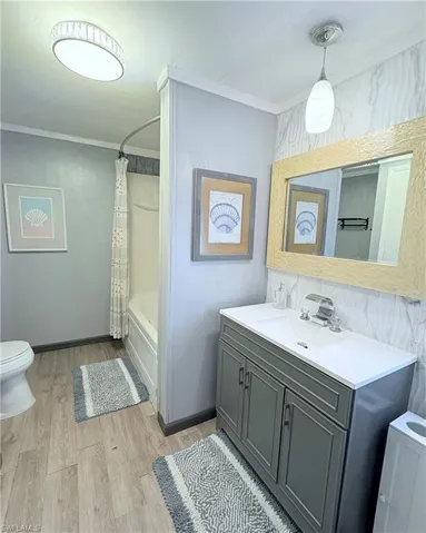 Bathroom with vanity, light wood-style flooring, shower / bath combo, and ornamental molding