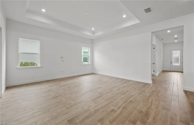 Unfurnished room with light hardwood / wood-style flooring and a raised ceiling