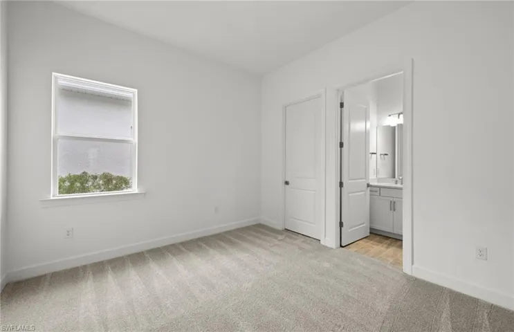 Unfurnished bedroom featuring ensuite bath and light colored carpet