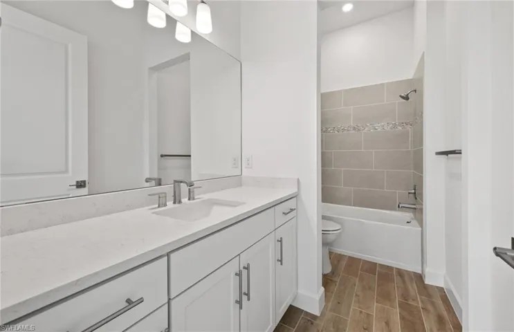 Full bathroom with vanity, tiled shower / bath combo, and toilet
