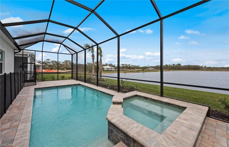 View of pool featuring an in ground hot tub, a water view, a patio area, and glass enclosure