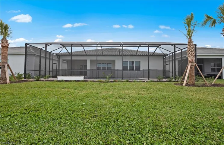 Rear view of property featuring a yard and glass enclosure
