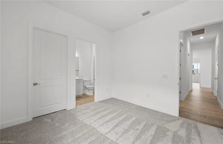 Unfurnished bedroom featuring light colored carpet and ensuite bathroom