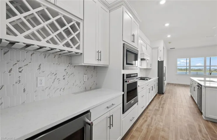 Kitchen featuring white cabinetry, light stone counters, wine cooler, and stainless steel appliances