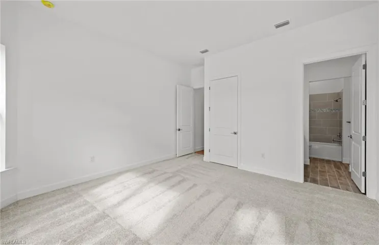 Unfurnished bedroom featuring connected bathroom and carpet flooring