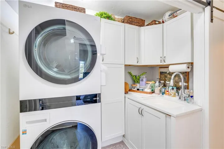 Laundry room featuring a barn door, sink, and stacked washer and clothes dryer