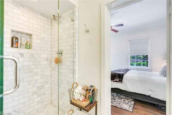 Bathroom featuring a shower with door, ceiling fan, and hardwood / wood-style floors