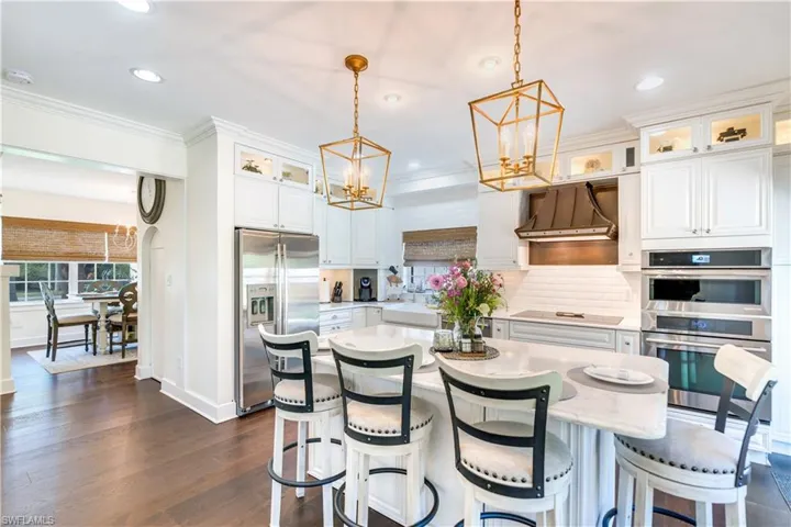 Kitchen featuring decorative light fixtures, a kitchen island, tasteful backsplash, custom exhaust hood, and appliances with stainless steel finishes