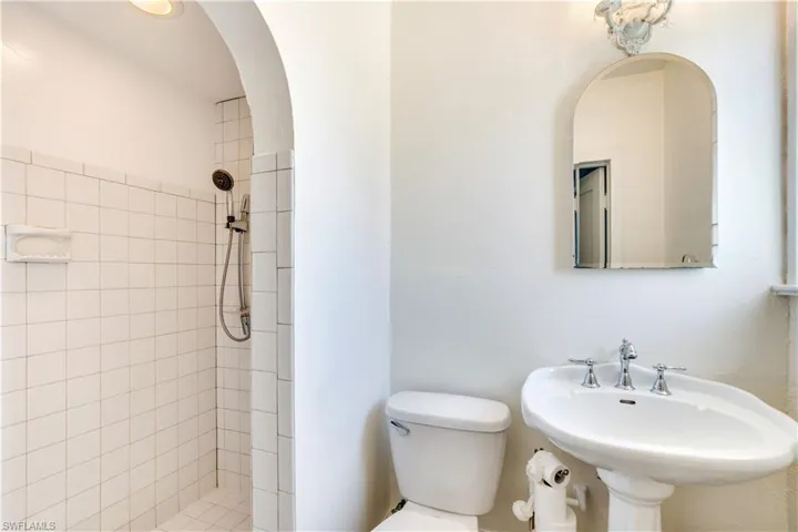 Bathroom featuring a tile shower, sink, and toilet