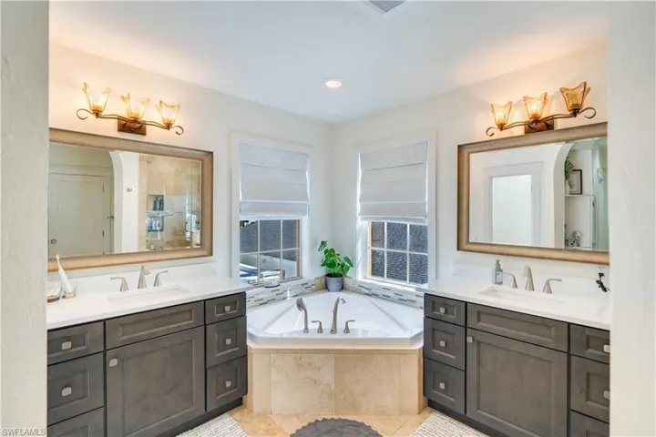Bathroom with tiled bath, oversized vanity, and double sink