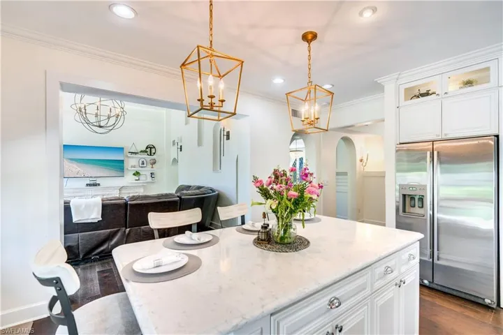 Kitchen featuring crown molding, high quality fridge, pendant lighting, dark hardwood / wood-style flooring, and a center island