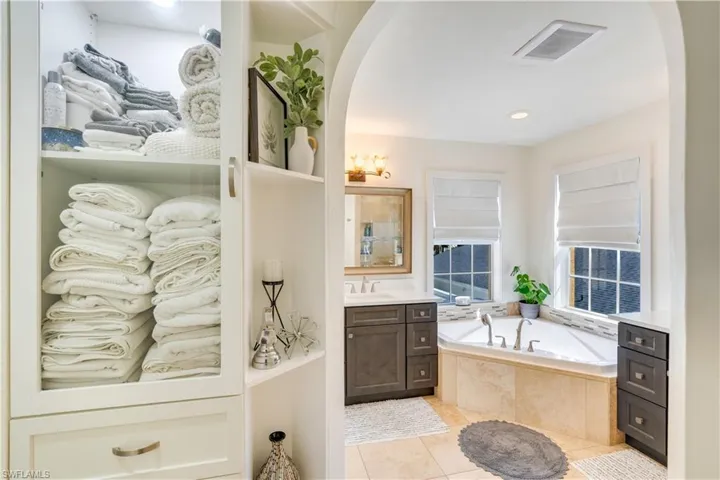 Bathroom featuring tile flooring, tiled tub, and vanity