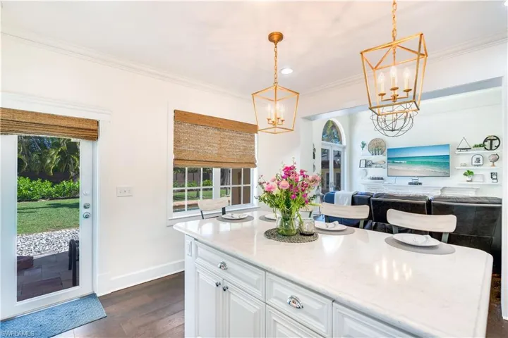 Kitchen with white cabinetry, light stone countertops, dark hardwood / wood-style floors, and pendant lighting