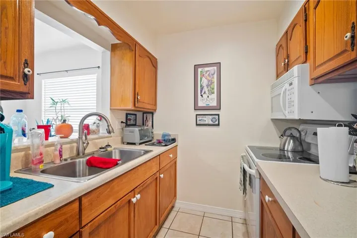 Kitchen featuring light tile patterned flooring, white appliances, and sink
