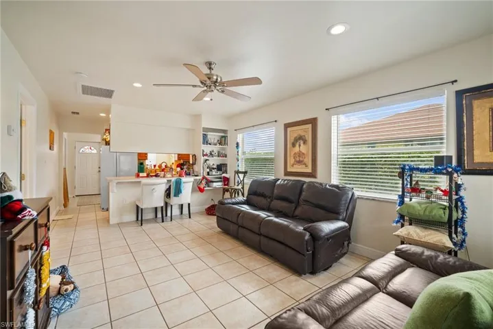 Living room with ceiling fan, built in features, and light tile patterned floors