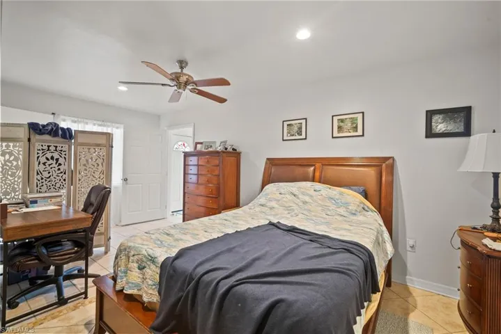 Tiled bedroom featuring ceiling fan