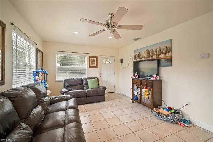 Tiled living room with ceiling fan and plenty of natural light