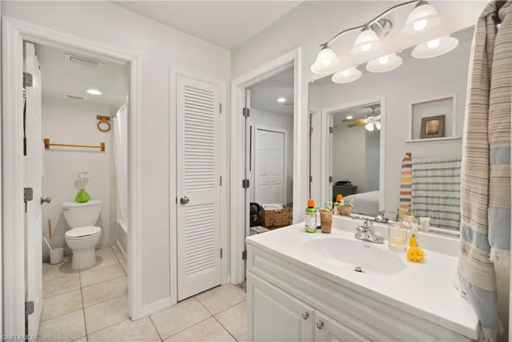 Full bathroom featuring tile patterned floors, vanity, shower / tub combo with curtain, ceiling fan, and toilet