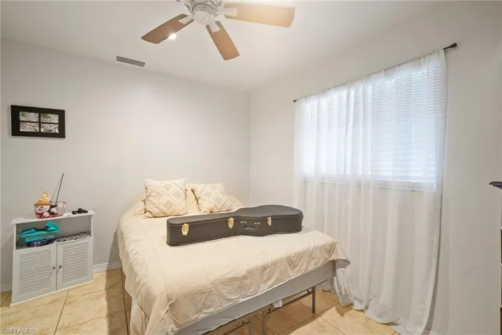 Tiled bedroom featuring ceiling fan