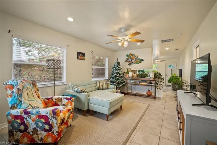 Living room with ceiling fan, light tile patterned flooring, and a healthy amount of sunlight