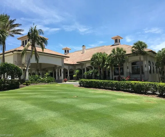 Rear view of house featuring a tile roof, a yard, and stucco siding