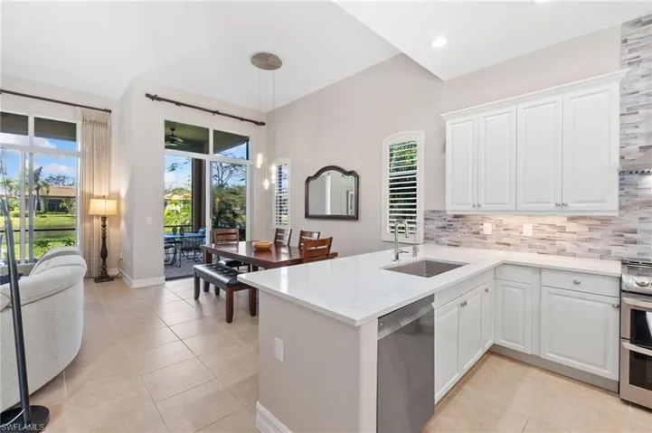 Kitchen featuring light tile patterned floors, tasteful backsplash, appliances with stainless steel finishes, a sink, and a peninsula