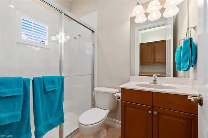 Bathroom with toilet, vanity, baseboards, a shower stall, and tile patterned floors