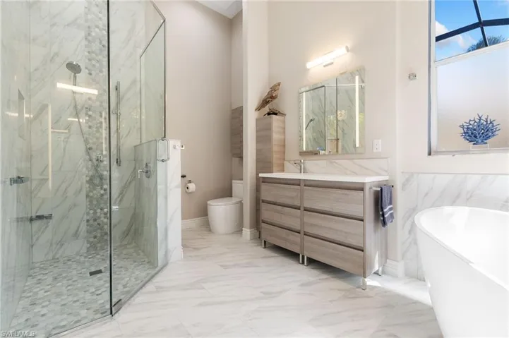 Full bath with a marble finish shower, toilet, a soaking tub, marble finish floor, and vanity