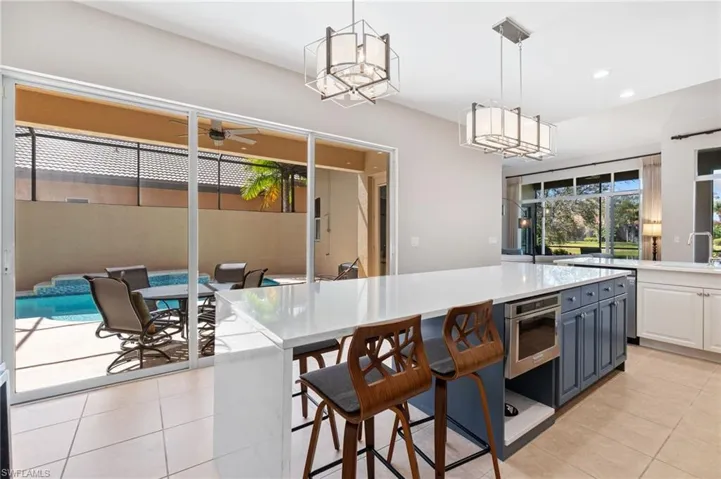 Kitchen featuring light countertops, stainless steel oven, decorative light fixtures, and light tile patterned floors