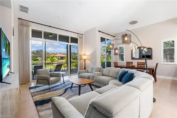 Living room featuring light tile patterned flooring, visible vents, and a healthy amount of sunlight