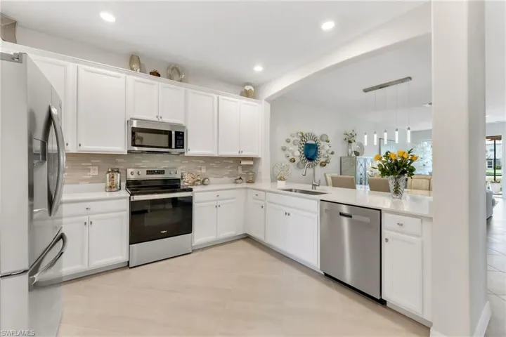 Kitchen featuring stainless steel appliances, white cabinets, quartz counters, new decorative backsplash