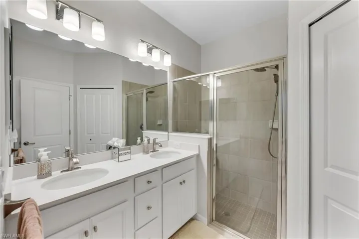 Full bathroom with double vanity and a shower stall