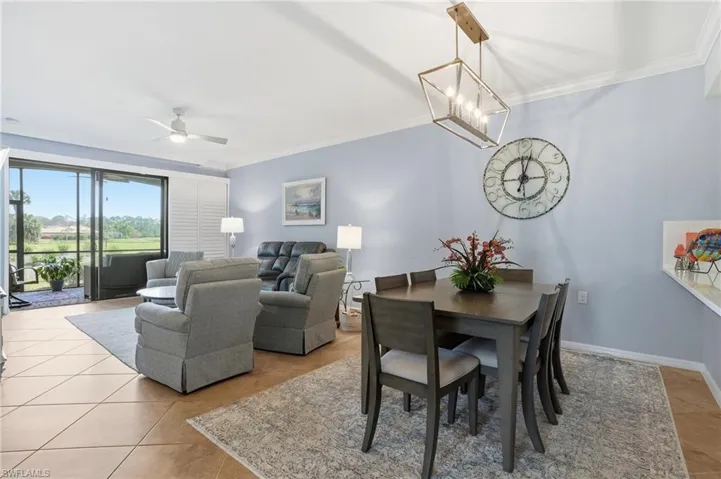 Dining room with crown molding, a ceiling fan, a chandelier, and light tile patterned floors