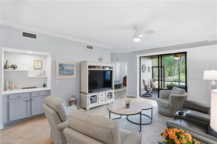 Living area with ornamental molding, ceiling fan, and light tile patterned flooring
