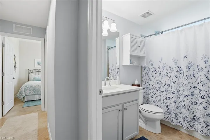 Bathroom with vanity, light tile patterned floors, curtained shower, and ensuite bathroom