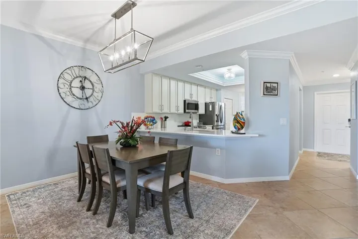 Dining room featuring crown molding, a chandelier, light tile patterned floors, and a tray ceiling