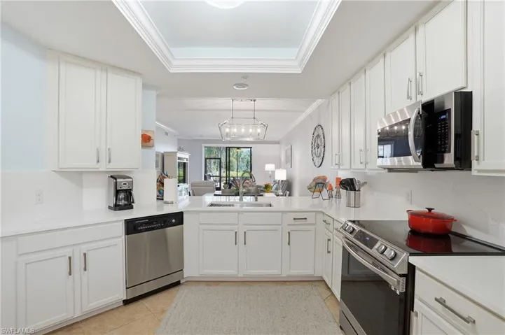 Kitchen featuring stainless steel appliances, white cabinets, tasteful backsplash, ornamental molding, and light tile patterned floors