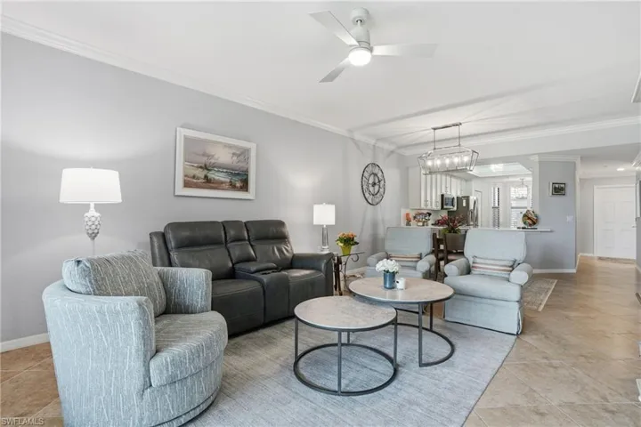 Living room featuring crown molding, ceiling fan, and light tile patterned floors