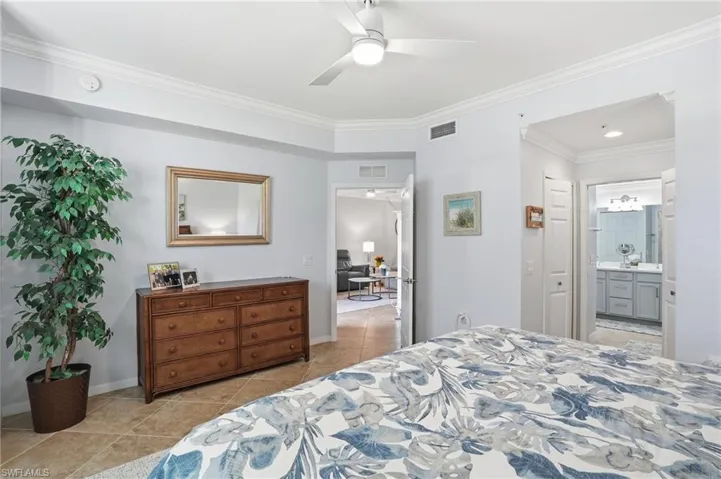 Bedroom featuring ornamental molding, ceiling fan, light tile patterned floors, and connected bathroom