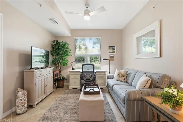 Living room with a ceiling fan and light tile patterned flooring