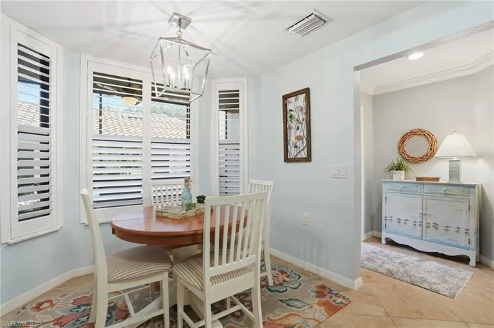Dining room with hanging lights, light tile patterned floors, and ornamental molding