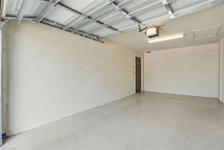 Garage featuring a garage door opener and concrete block wall