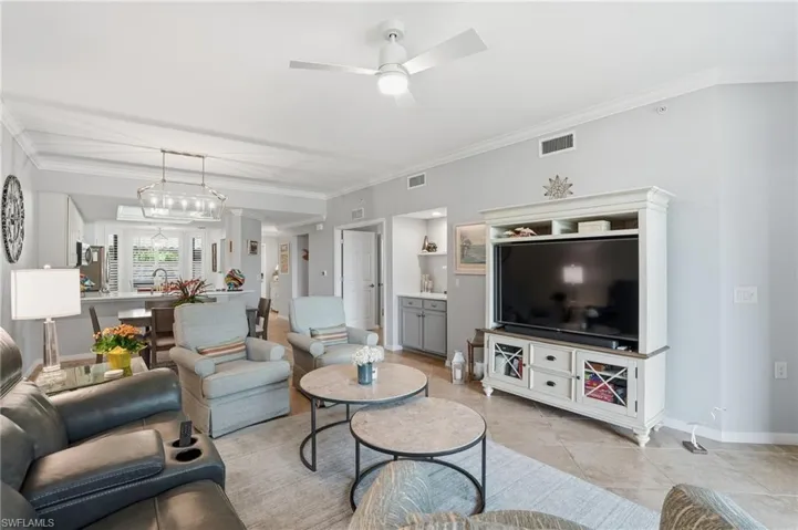 Living area featuring ornamental molding, ceiling fan, hanging lights, and light tile patterned floors