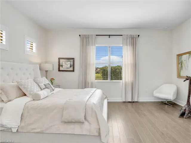 Bedroom with multiple windows, wood finished floors, and baseboards