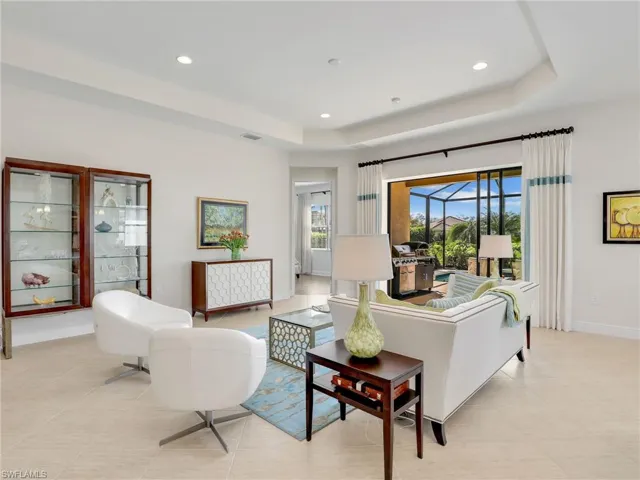 Living area with a tray ceiling, recessed lighting, visible vents, and baseboards