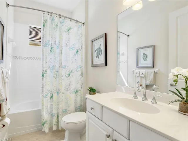 Bathroom with toilet, shower / bath combo with shower curtain, and vanity